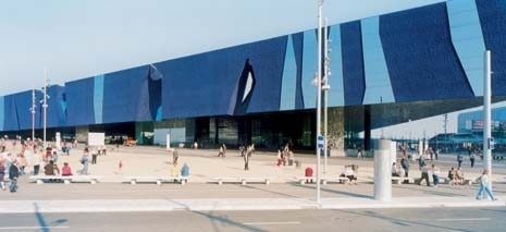 Il Centro Congressi di Herzog & de Meuron si sviluppa in un compatto volume triangolare piano. Il programma – che comprende un auditorium, aree espositive, uffici e ristoranti – è organizzato orizzontalmente. Sotto la copertura aggettante, una sorta di grande mantello, si raccolgono le persone per trovare un po’ d’ombra