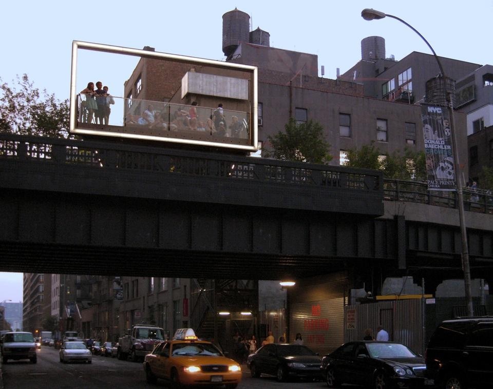 Il 26th Street Viewing Spur visto dalla strada. Una grande struttura luminosa sul bordo della piattaforma evoca contemporaneamente un cartellone pubblicitario, un arco di proscenio, una vetrata, un mirino. Photo by Gideon Fink Shapiro