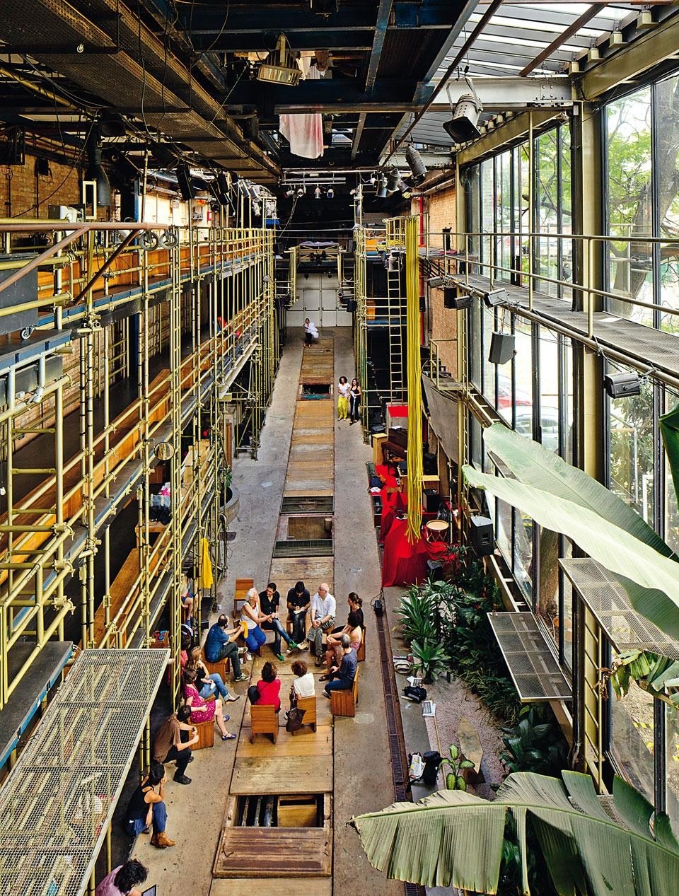 Senza precisa divisione degli ambiti, pubblico e attori condividono arredi, apparati tecnici e spazi durante le rappresentazioni. Sullo sfondo i due varchi dai quali è possibile ‘fuggire’ nei terreni adiacenti