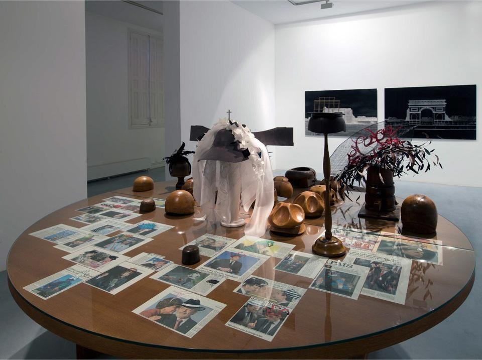 <i>Prêt-à-porter</i> di Carlos Garaicoa è l'installazione centrale della mostra "Party! Not Tea Party" alla Galería Elba Benítez. Consiste in un grande tavolo su cui sono disposte numerose vecchie forme di legno da modista e alcuni copricapo. © Carlos Garaicoa
Courtesy dell'artista e della Galería Elba Benítez.
Photo Luis Asín.
