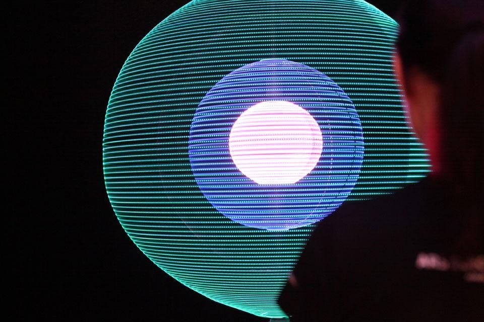 The Particle, dello spagnolo Alex Posada, è una scultura cinetica costituita da anelli di LED multicolori che producono forme luminose di grande bellezza, metafora dell'effimero ordine emerso dal caos primordiale.
