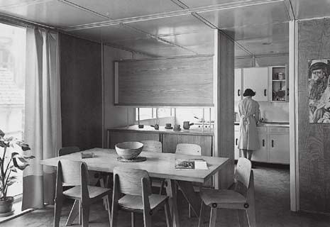 Interno di una maison Métropole a portico assiale, 1950. Quando fonda Les Ateliers Jean Prouvé nel 1931 la società è interamente votata alla produzione di “costruzioni metalliche, case industrializzate” e “mobili smontabili di costruzione mista metallo e legno”: l’approccio globale alla costruzione di Prouvé non implica separazione tra mobili e casa