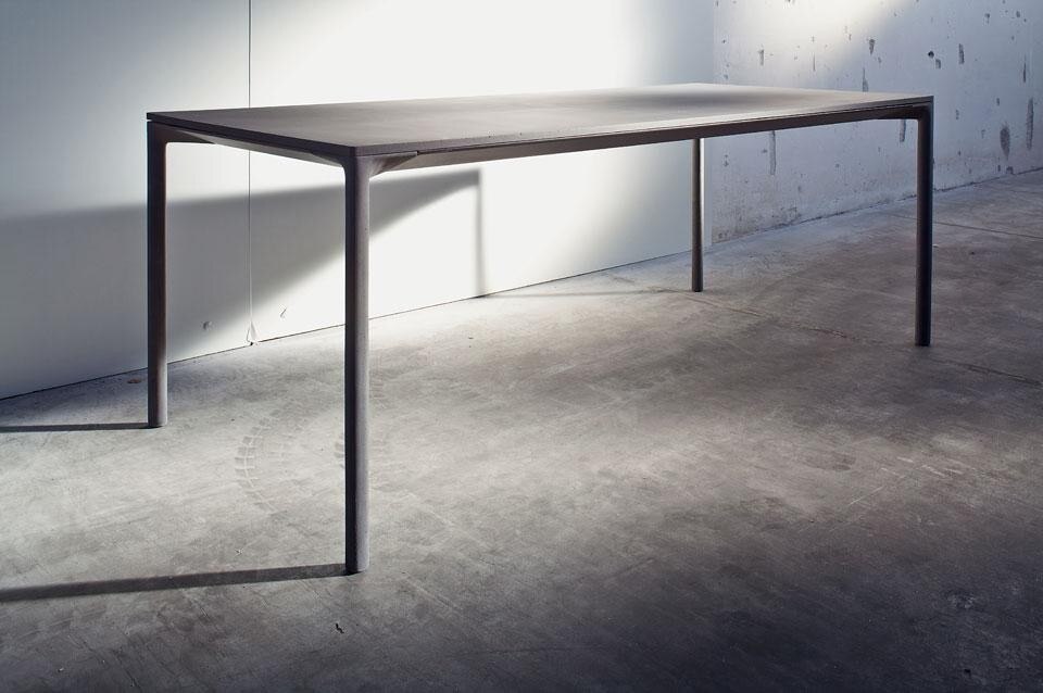 La gamba integra l’aggancio al longherone che sostiene il piano del tavolo: l’uso del cemento si combina con un’anima metallica per alleggerire l’insieme. La gamba pesa circa 3,5 Kg.
Il piano monolitico ha uno spessore di 13 mm