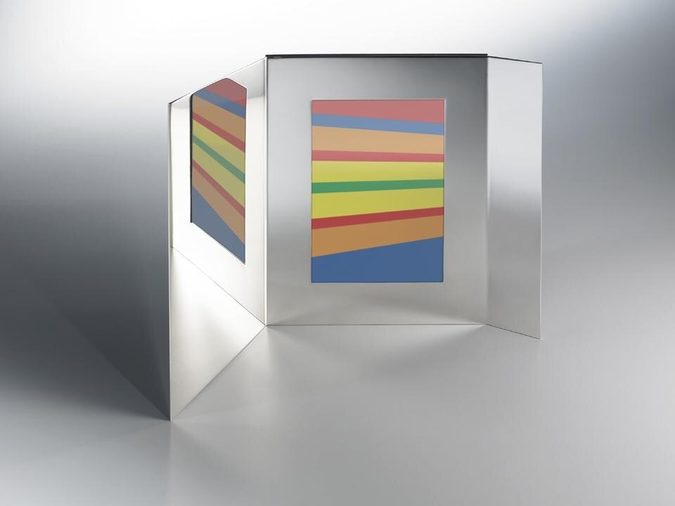 La cornice Dialogo a due prevede due lastre laterali piegate e aperte per costituire un ambito più esteso ma confinato tra propria immagine e fotografia.