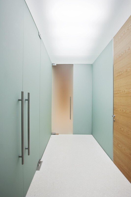 I clienti vengono accolti da una parete luminosa realizzata con doppio vetro, uno opalino, l'altro trasparente e, nel mezzo, lamelle di rovere massello naturale