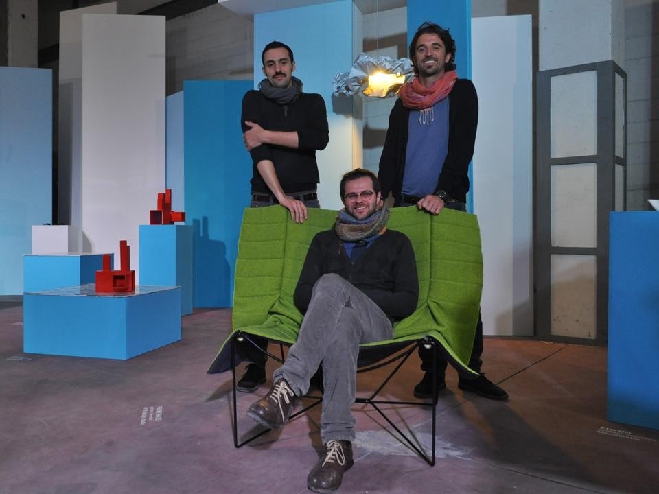 Lo studio 4P1B sulla poltrona Promenade, che reinterpreta l'idea di poltrona con una coperta trapuntata tesa su una struttura in metallo. Sullo sfondo, la lampada Nimbo, con paralume in tessuto catarifrangente in cui l'utente può modificare la forma arricciando o piegando il materiale