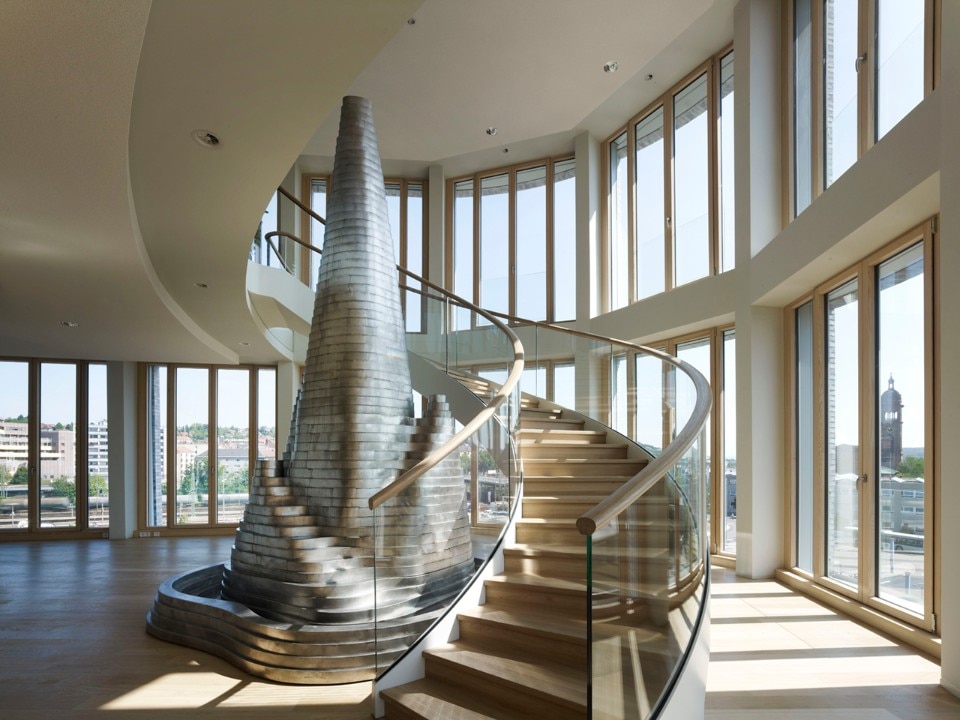 La scala a spirale con struttura di acciaio e rivestimento in legno collega il quinto e il sesto piano