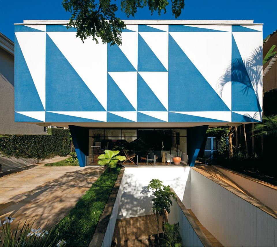 Facing the road,
the front of the Rubens de Mendonça House
was treated as if it were a gigantic mural work of
art. Vilanova Artigas involved Mário Gruber and
Rebolo Gonzales in the design of the facades
of the house for Rubens de Mendonça.
“The fresco was created by Rebolo based
on the studies I did with Gruber.”
The geometric pattern on the building’s
facade gave rise to the nickname “House
of Triangles”. Here again, a colour theme
was used: on the exterior, white and blue
triangles are interspersed with pink panels. Facing the road,
the front of the Rubens de Mendonça House
was treated as if it were a gigantic mural work of
art. Vilanova Artigas involved Mário Gruber and
Rebolo Gonzales in the design of the facades
of the house for Rubens de Mendonça.
“The fresco was created by Rebolo based
on the studies I did with Gruber.”
The geometric pattern on the building’s
facade gave rise to the nickname “House
of Triangles”. Here again, a colour theme
was used: on the exterior, white and blue
triangles are interspersed with pink panels.